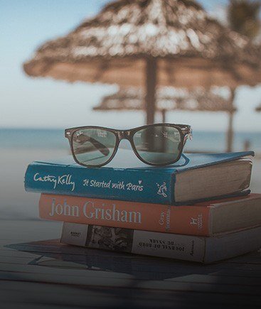 Imagen de gafas sobre libros en la playa